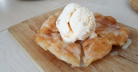 Vanilla ice cream on crispy fried roti on wood block