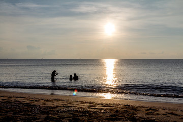 Fototapeta premium Father, mother, and child Enjoy the sea at dawn