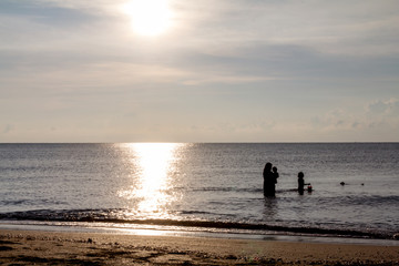 Fototapeta na wymiar Father, mother, and child Enjoy the sea at dawn.