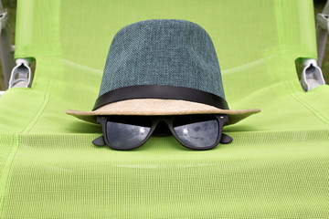 Straw hat with black glasses on a green chair