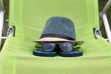 Straw hat with black glasses on a green chair