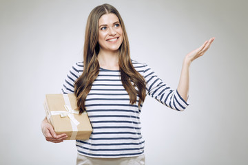 Smiling woman holding gift box presenting empty hand.