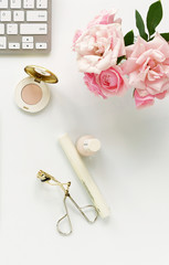 Beauty blog concept. Female make up accessories and bouquet of pink roses on white background. Flat lay, top view feminine desk, workspace with laptop
