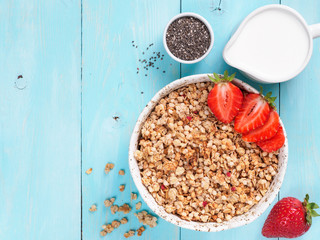 bowl with muesli, fresh strowberry, chia seeds and milk in milk jug