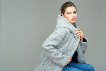 Beautiful girl wearing gray coat with hood. Isolated portrait.