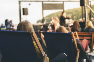 People sitting in loungers on beach listening to the concert