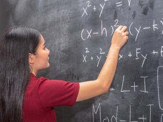 Young beautiful girl in the classroom, writing a black board