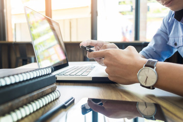 Smiling young casual business man with mobile phone in the hand in office