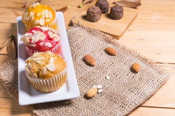 Sweet muffins with almond on  wooden table.