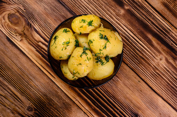 Boiled young potatoes in glass bowl on wooden table. Top view