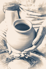 Obraz na płótnie Canvas Potter holds more crude to the firing of white clay jug. Sculptor sculpts pots products from white clay. Master keeps on empty hands open earthen vessel. Workshop pottery. Old vintage style.