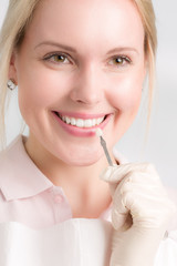Zahnarzthelferin zeigt, wie die Zahnfarbe für einen Zahnersatz bestimmt wird