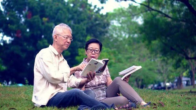 Asian senior couple reading books at the park.Spend quality time and never stop learning something new 4k