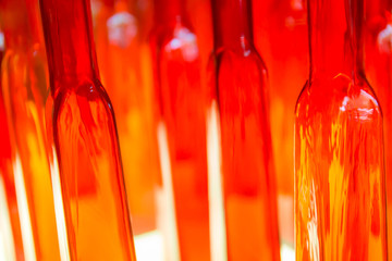 Abstract blurred photo of textured red and clear glass bottles in warm lights for interior decorations.