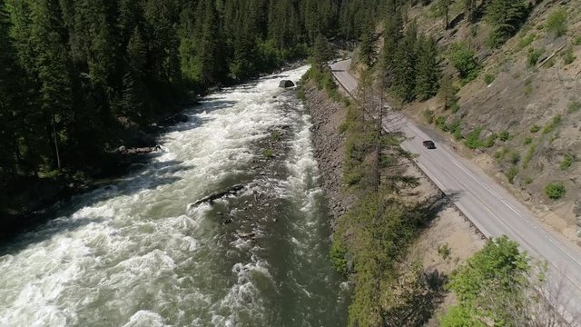 Drone Following Car on Roadtrip Traveling Mountain Road by Scenic Canyon River