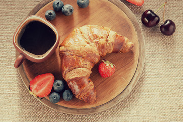 Coffee cup, fresh croissant and berries 