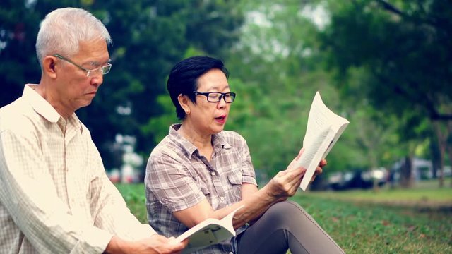Asian senior couple reading books at the park.Spend quality time and never stop learning something new 4k