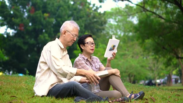 Asian senior couple reading books at the park.Spend quality time and never stop learning something new 4k