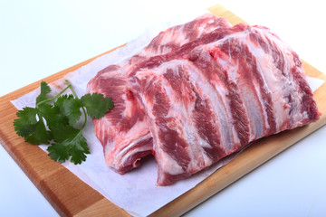 Raw pork ribs with herbs and spices on wooden board. Ready for cooking.