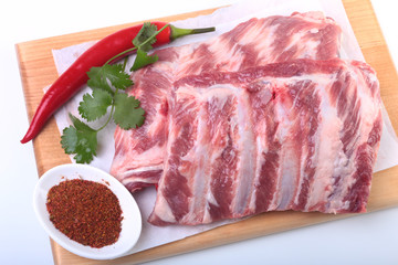Raw pork ribs with herbs and spices on wooden board. Ready for cooking.