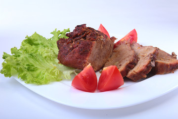 Steak of grilled meat with tomato, lettuce and beans pomegranate on white plate.