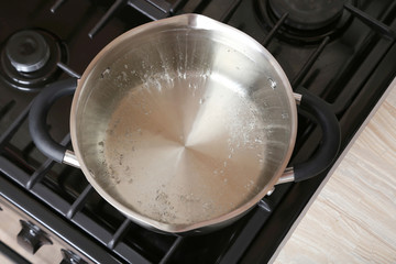 Water boiling into saucepan on the gas stove