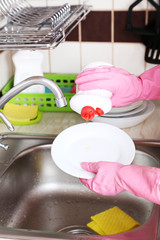 Fototapeta na wymiar Female hands in gloves washing dish