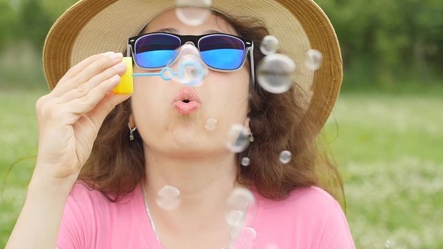 Woman blowing soap bubbles at sunset