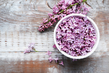 Fototapeta na wymiar Lilac flowers in bowl on wooden table