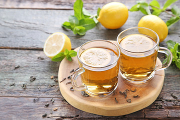 Cup of tea with lemon and mint on wooden table