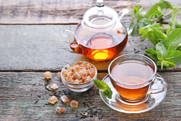 Cup of tea with teapot and sugar on grey wooden table