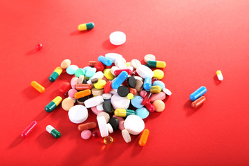 Different colorful pills on red background