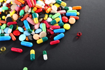 Different colorful pills on black background