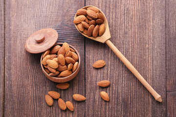 Almonds in bowl and spoon on brown wooden table