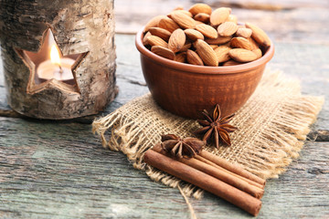 Fototapeta na wymiar Almonds in bowl with cinnamon and star anise on wooden table