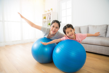 mother and her daughter lying on the ball