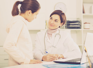 Fototapeta premium Doctor fills patient card for girl