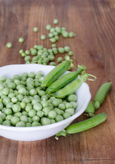 Guisantes en plato sobre fondo de madera