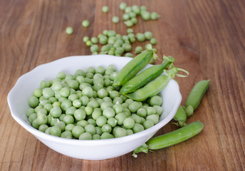 Guisantes en plato sobre fondo de madera