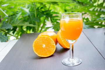 Glass of freshly pressed orange juice with sliced orange half on wooden table