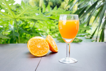 Glass of freshly pressed orange juice with sliced orange half on wooden table