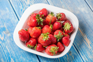 Ripe red strawberries in white bowl.