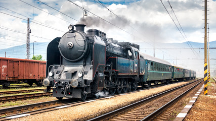 Train with a steam locomotive coming to the railway station.