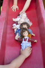 Two children playing with five dolls on a slide