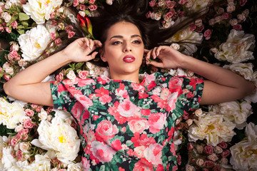 Sensual woman lying on flowers in studio photo. Beauty and fashion. Cosmetics and skincare