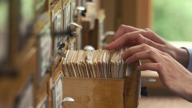 Student checks cards with books' names in the library