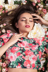 Lovely woman lying on flowers in studio photo. Beauty and fashion. Cosmetics and skincare