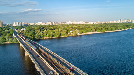 Fototapeta na wymiar Aerial top view of Metro railway bridge with train and Dnieper river from above, skyline of city of Kiev, Ukraine 