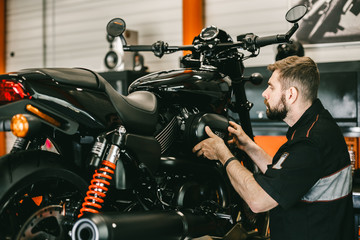Professional mechanic change the air filter in the motorcycle. Handsome young man repairing motorcycle in repair shop.
