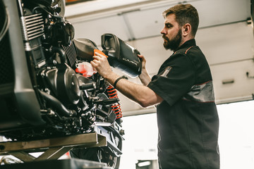 Motorcycle mechanic replacing and pouring fresh oil into engine at maintenance repair service...